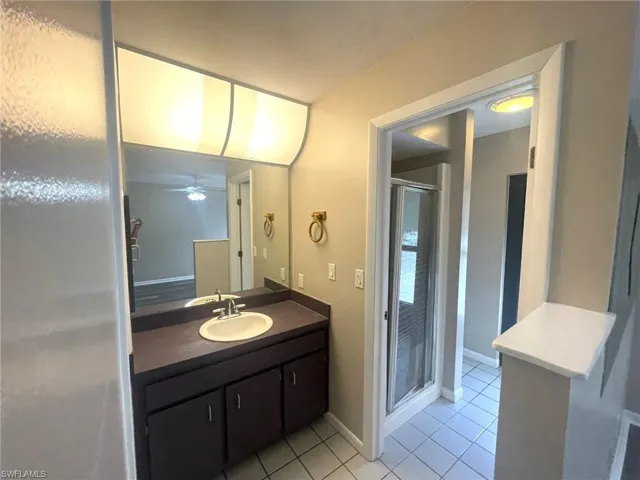 Bathroom with tile patterned flooring, vanity, ceiling fan, and a shower with door