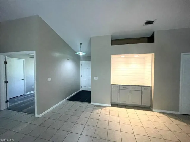 Spare room featuring light tile patterned floors and high vaulted ceiling