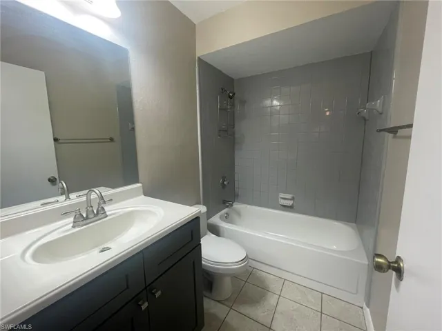Full bathroom featuring vanity, tile patterned flooring, toilet, and tiled shower / bath combo