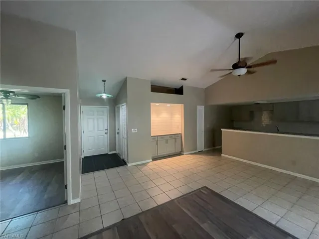 Unfurnished living room featuring ceiling fan, light tile patterned floors, and high vaulted ceiling