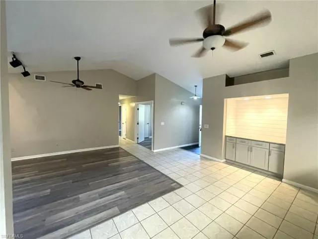 Unfurnished room with light tile patterned floors, ceiling fan, and vaulted ceiling