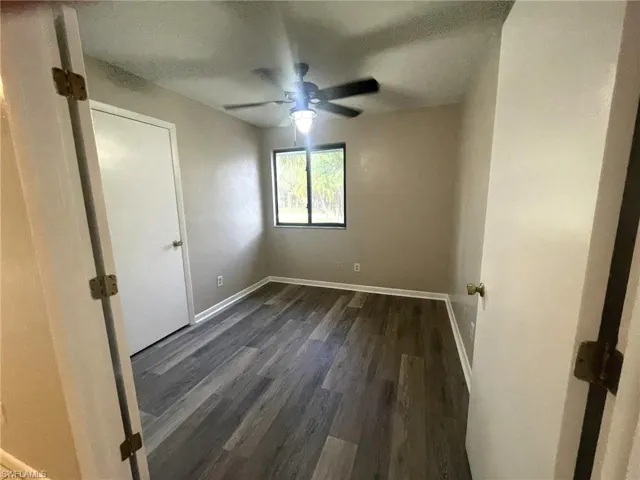 Unfurnished room with a textured ceiling, dark hardwood / wood-style floors, and ceiling fan