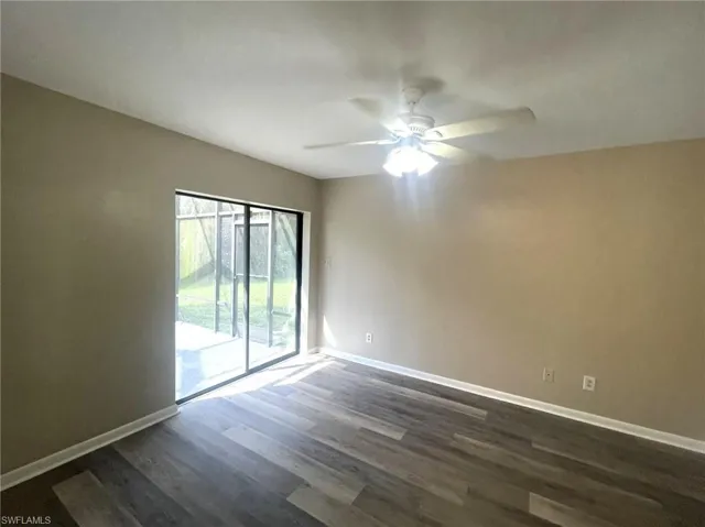Unfurnished room featuring dark wood-type flooring and ceiling fan