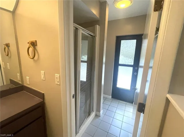 Bathroom featuring walk in shower, tile patterned flooring, and vanity