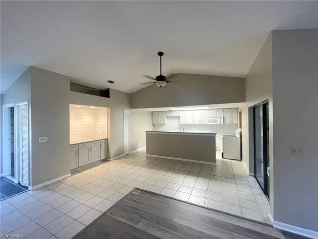 Kitchen featuring lofted ceiling, sink, light tile patterned floors, and ceiling fan