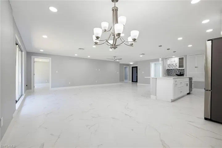 Kitchen with an island with sink, white cabinetry, pendant lighting, open floor plan, and freestanding refrigerator