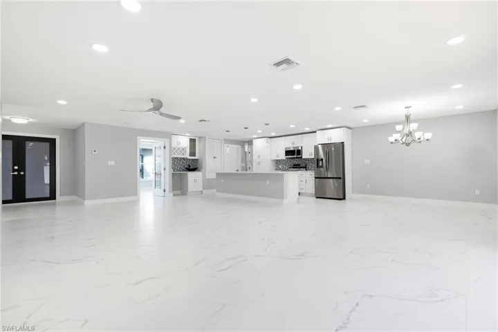 Unfurnished living room with light marble finish floors, recessed lighting, a ceiling fan, a chandelier, and french doors