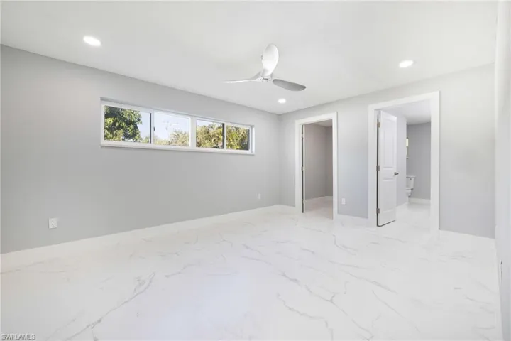 Unfurnished bedroom with light marble finish flooring, recessed lighting, ceiling fan, a spacious closet, and connected bathroom