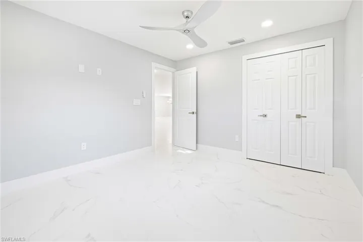 Guest bedroom featuring light marble finish floors, a closet, recessed lighting, and ceiling fan