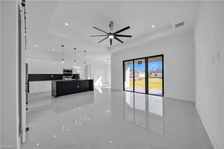 Unfurnished living room featuring ceiling fan, a raised ceiling, and recessed lighting