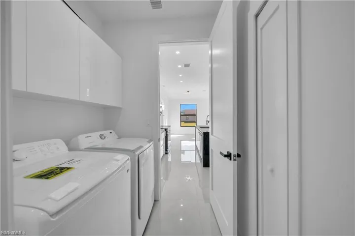 Laundry room with cabinet space, washer and clothes dryer, recessed lighting, and light tile patterned flooring