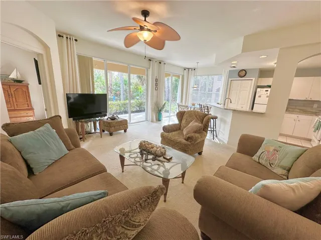 Living room with plenty of natural light, a ceiling fan, and light colored carpet