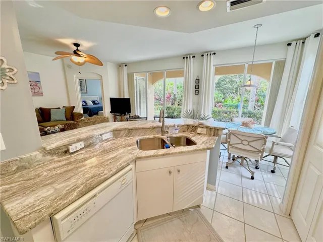 Kitchen featuring dishwasher, light stone counters, decorative light fixtures, light tile patterned floors, and recessed lighting