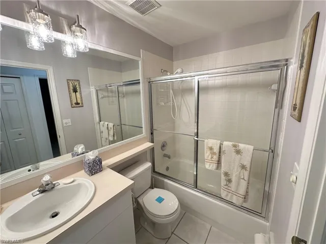 Full bath featuring vanity, tile patterned flooring, and shower / bath combination with glass door