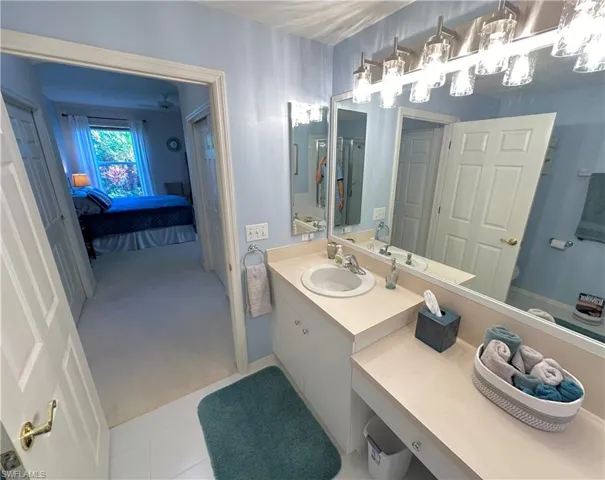 Bathroom featuring vanity, ensuite bath, light carpet, and light tile patterned floors