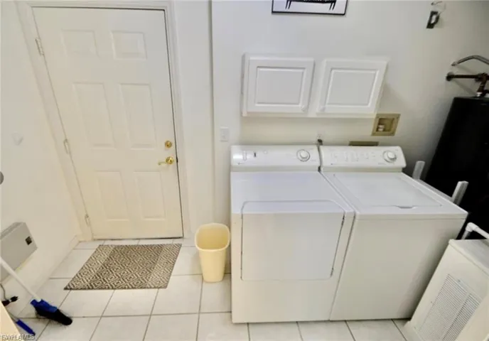 Laundry area featuring light tile patterned floors and independent washer and dryer