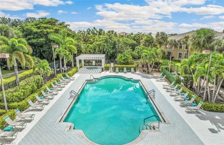 Community pool with a patio area and view of scattered trees