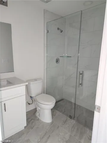 Bathroom with vanity and a marble finish shower