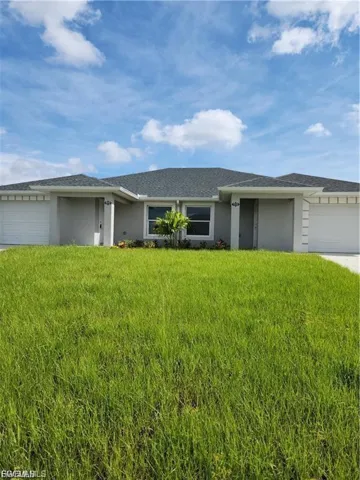 Ranch-style home with a garage, concrete driveway, stucco siding, and a front yard