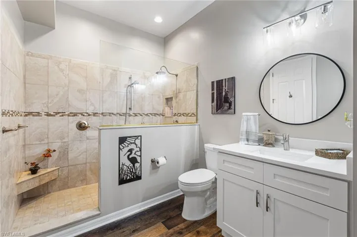 This oversized second bathroom impresses with a quartz-topped vanity and a spacious walk-in shower featuring porcelain tile walls, an elegant listello accent, a rain shower head, and a handheld wand for a fully customized spa-like experience.