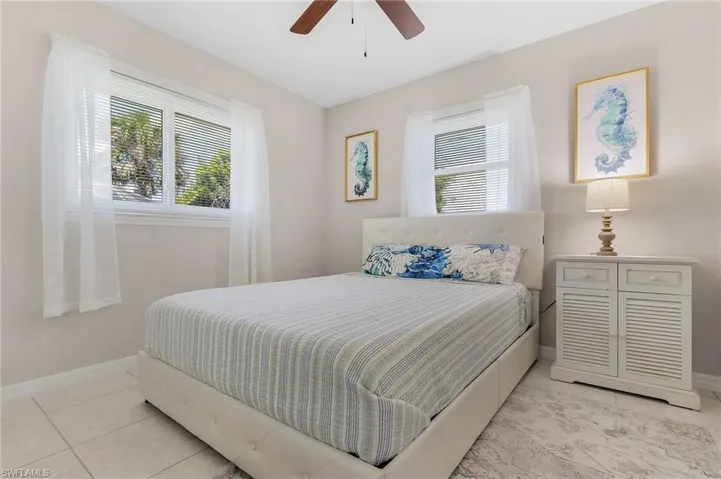 Tiled bedroom featuring ceiling fan