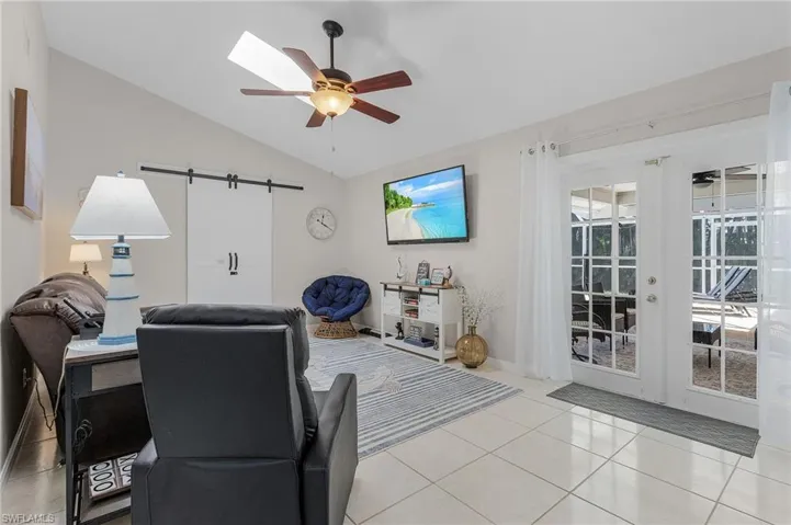 Living room featuring plenty of natural light, light tile flooring, ceiling fan, and vaulted ceiling