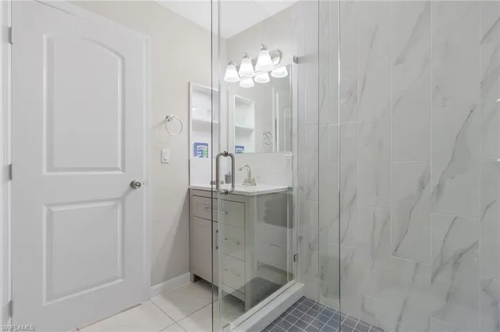Bathroom with an enclosed shower, tile floors, and large vanity