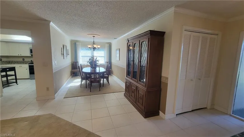 Dining room featuring an inviting chandelier, ornamental molding, a textured ceiling, and light tile patterned floors