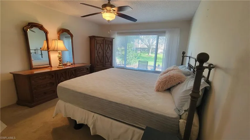 Carpeted bedroom featuring ceiling fan and a textured ceiling
