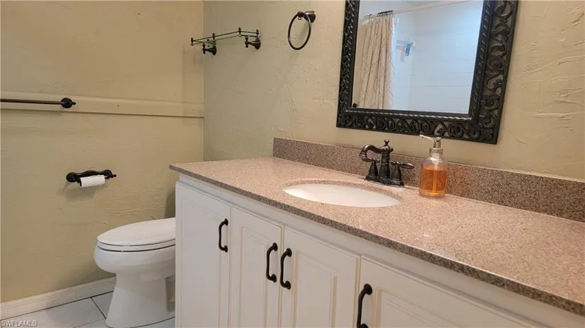 Bathroom with vanity, a shower with curtain, tile patterned floors, and toilet
