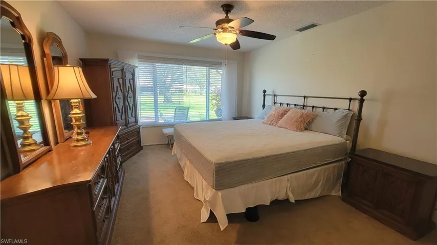 Bedroom featuring ceiling fan, light colored carpet, and a textured ceiling