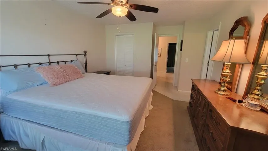 Carpeted bedroom with ceiling fan and a closet