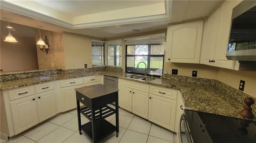 Kitchen featuring white cabinetry, a raised ceiling, sink, and dark stone countertops