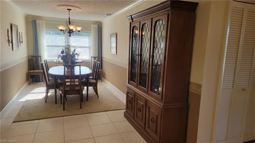 Dining area featuring a notable chandelier, light tile patterned floors, ornamental molding, and a textured ceiling
