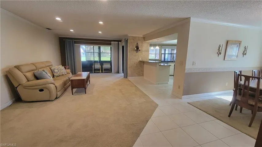 Living room with ornamental molding, a textured ceiling, and light tile patterned floors