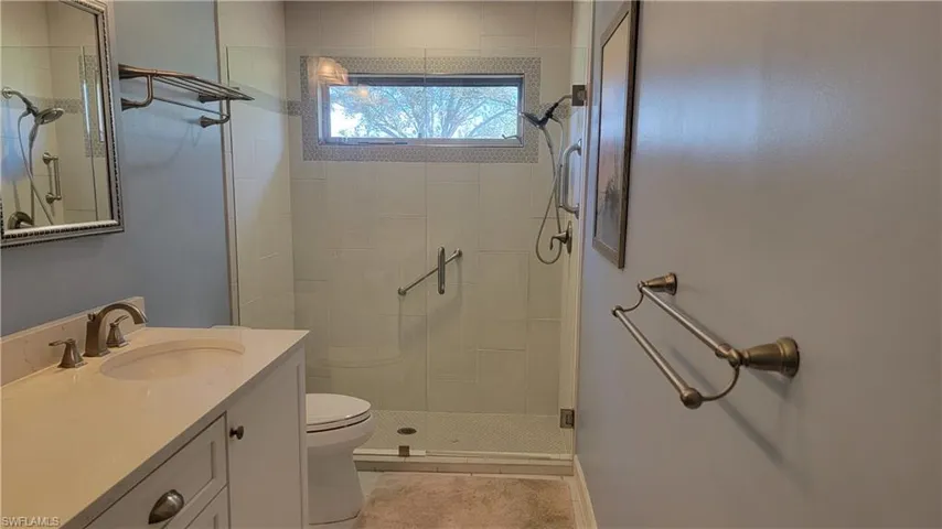 Bathroom with a shower with door, vanity, tile patterned floors, and toilet