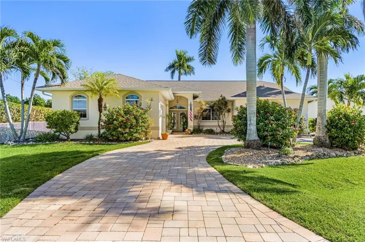 Ranch-style home featuring a front yard, decorative driveway, stucco siding, and french doors