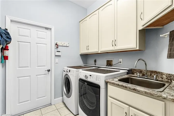 Laundry room with light tile patterned floors, washer and dryer, and cabinet space