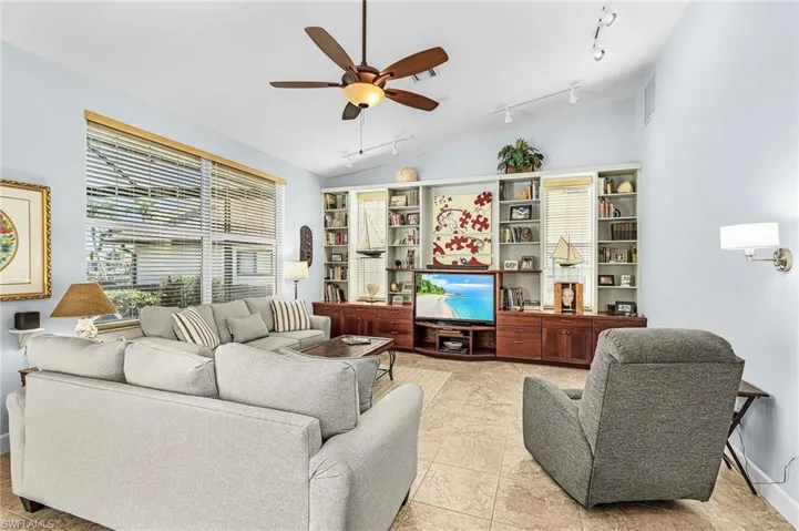 Living room featuring a ceiling fan, vaulted ceiling, track lighting, and light tile patterned floors