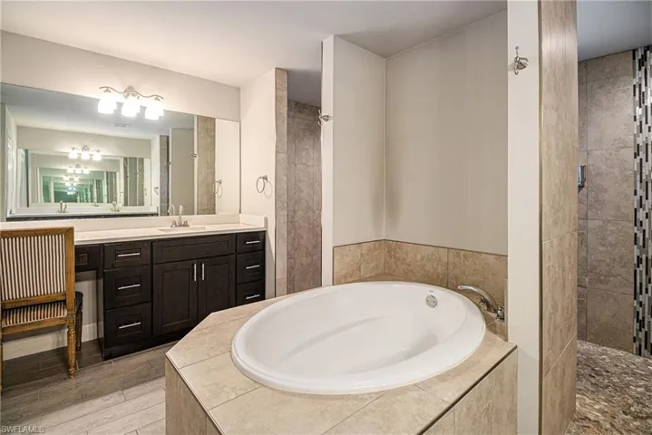 Full bath with a garden tub, vanity, and tiled shower