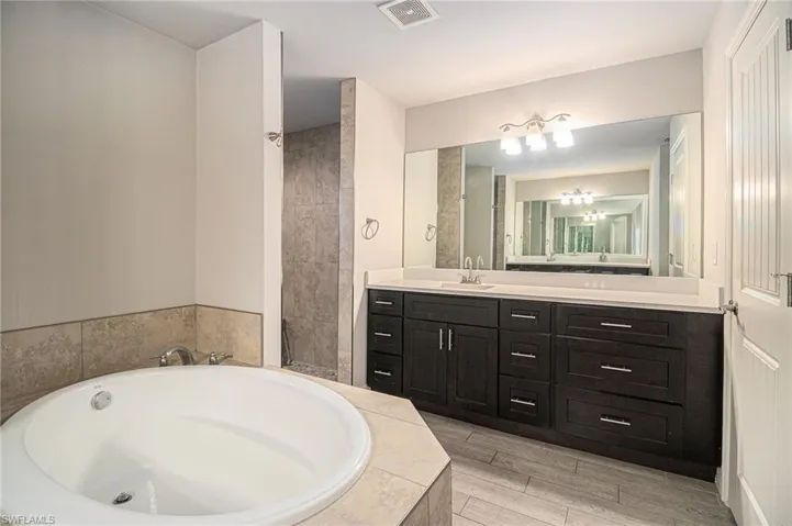 Bathroom with a garden tub, vanity, wood finish floors, and a chandelier
