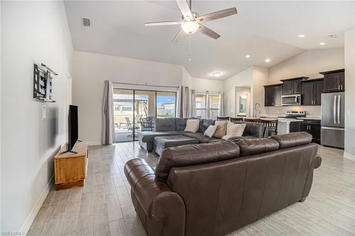 Living area with tile wood-style floors, ceiling fan, and high vaulted ceiling