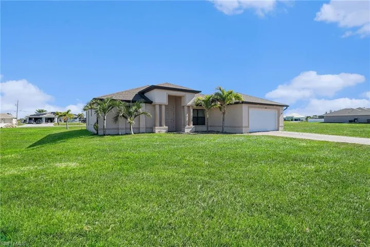 View of front of property with a front lawn, driveway, stucco siding, and a garage
