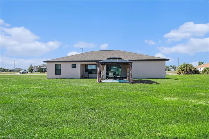 Rear view of property featuring a yard, a gazebo, a patio, and stucco siding