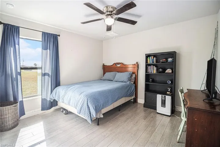 Bedroom 2 with tilke wood-style floors and a ceiling fan