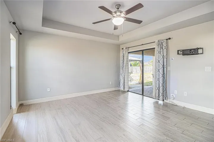 Unfurnished room featuring a raised ceiling, tile wood-style flooring, and ceiling fan