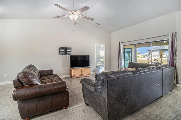 Living room with tile wood-style flooring, high vaulted ceiling, and ceiling fan