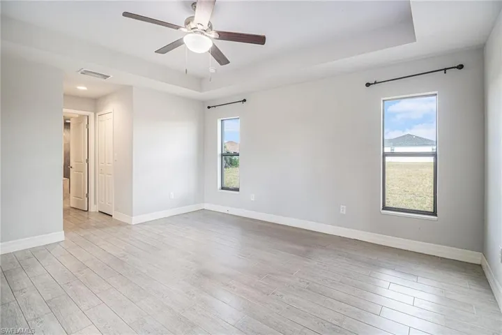 Unfurnished room featuring a tray ceiling, tile wood-style floors, and a ceiling fan