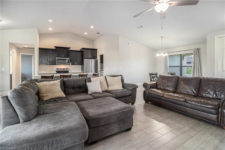 Living area featuring ceiling fan, tile wood finished floors, a chandelier, and high vaulted ceiling