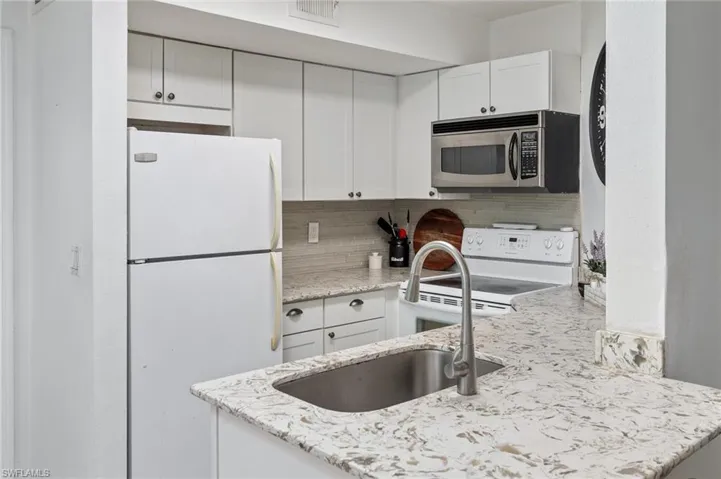 Kitchen featuring white cabinets and light stone counters